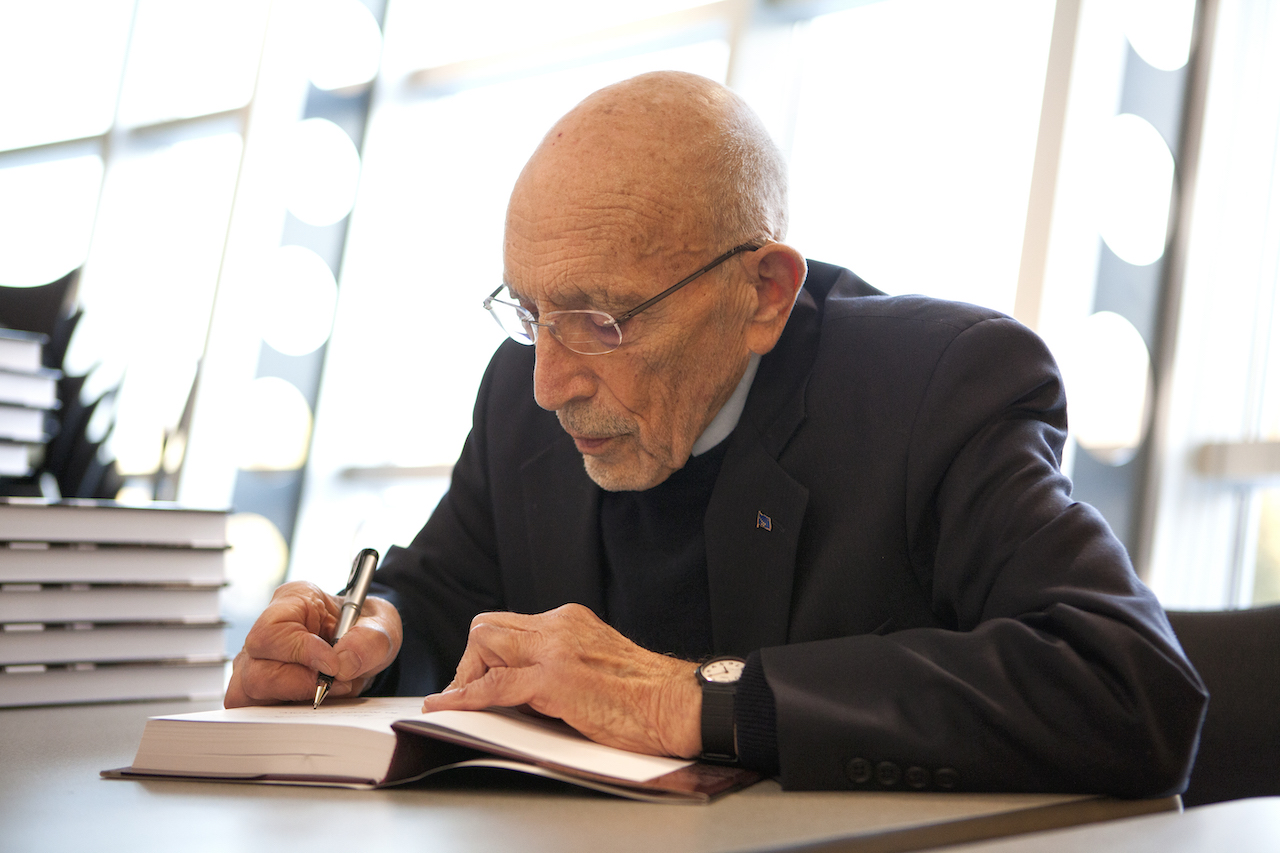 Vic Fischer, author and director emeritus of ISER signs copies of his new book "To Russia With Love, An Alaskan's Journey" at a reception at the UAA/APU Consortium Library in 2012.