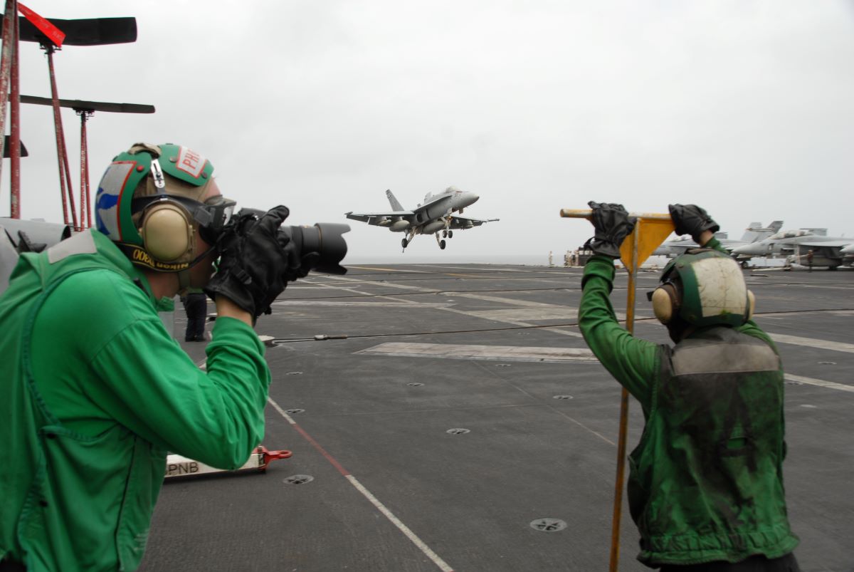 a US Navy photographer on the deck of an aircraft carrier
