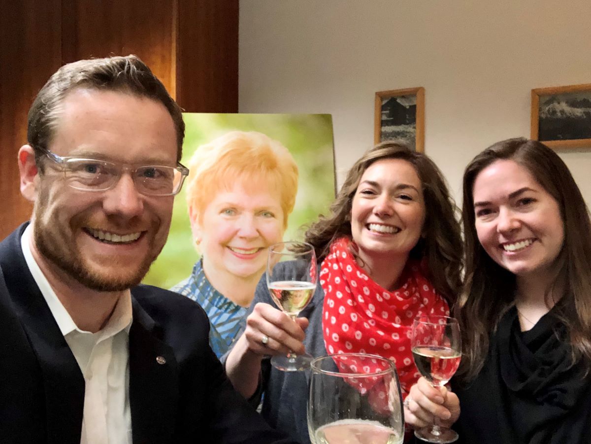 Ben Linford, Becky Linford Love and Brenna Linford raise their glasses in memory of their grandmother, Sue “Tutu” Linford, whose photo is in the background.