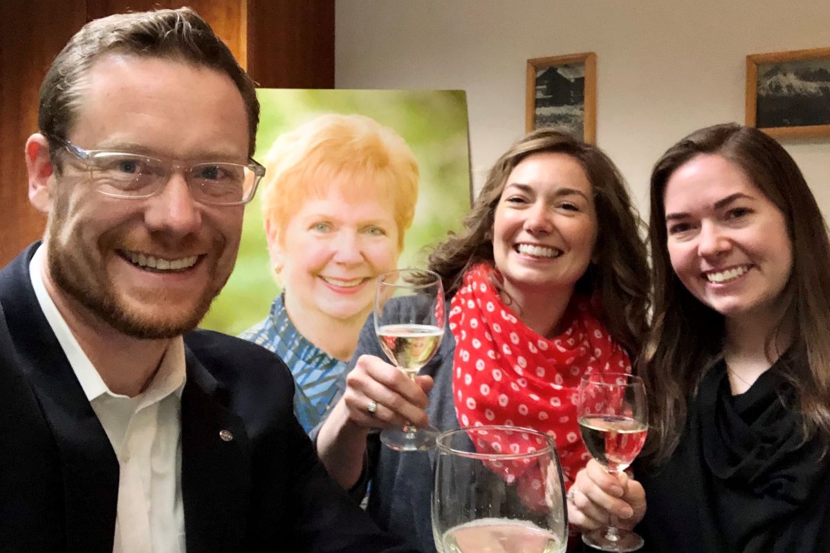 Ben Linford, Becky Linford Love and Brenna Linford raise their glasses in memory of their grandmother, Sue “Tutu” Linford, whose photo is in the background.