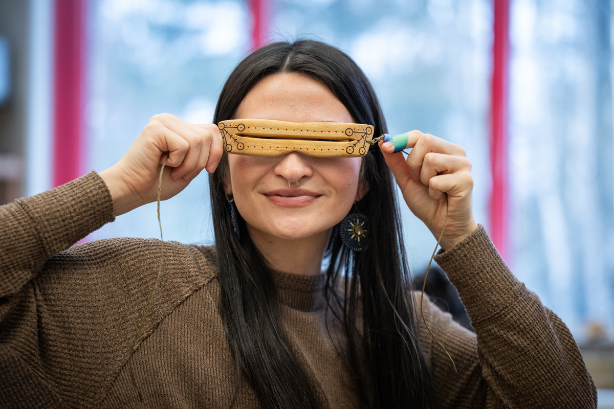 Student Taytum Robinson learns to make Inupiaq-style snow goggles from visiting artist Leon Kinneeveauk during June Pardue's Alaska Native Arts class in UAA's Fine Arts Building. (Photo by James Evans / University of Alaska Anchorage)