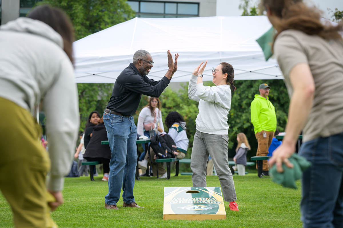 ANSEP Acceleration Academy Assistant Director Marvin Johnson and ANSEP Student Success Coordinator Angelica Afcan play cornhole during UAA's July 2024 Concert in the Quad.