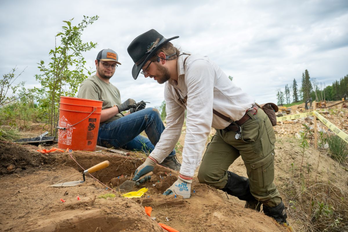 two archaeology students excavating at a dig