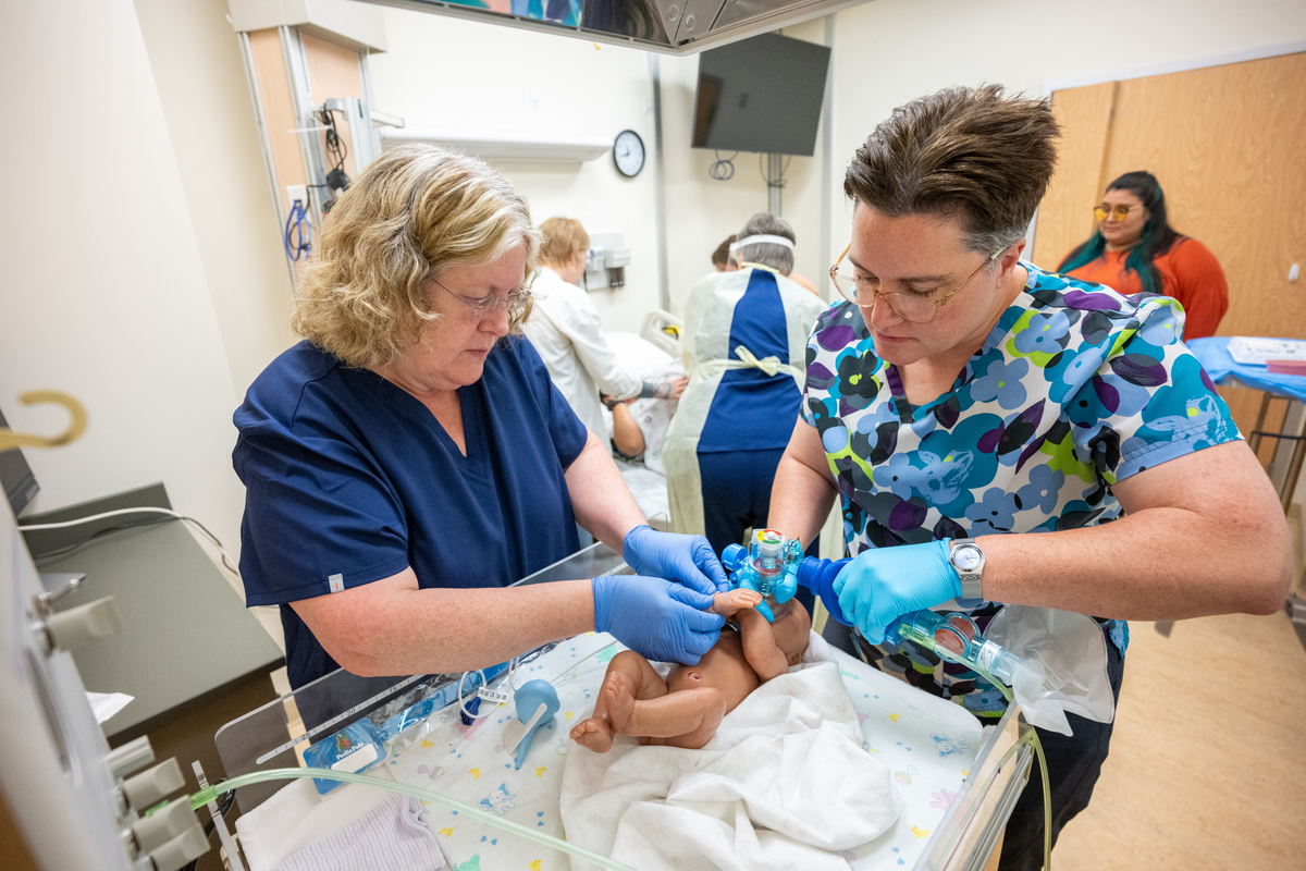 Simulation Center Director Sara Hannon and nurse role player Annette McNab simulate newborn infant care while student doulas help Bethany Alvarez, portraying the expectant mother, as UAA College of Health Simulation Center uses a wearable Avbirth Childbirth Simulation Device for the first time to help train students in the Full Embrace Doula Program, which provides comprehensive education, mentorship, and capacity-building to expand access to culturally attuned birth support in Alaska.