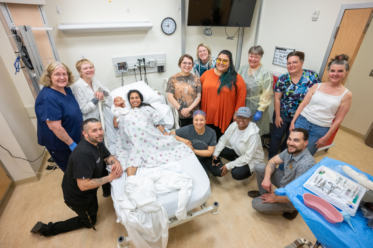 Simulation participants gather to celebrate a successful (simulated) birth as UAA College of Health Simulation Center uses a wearable Avbirth Childbirth Simulation Device for the first time to help train students in the Full Embrace Doula Program.