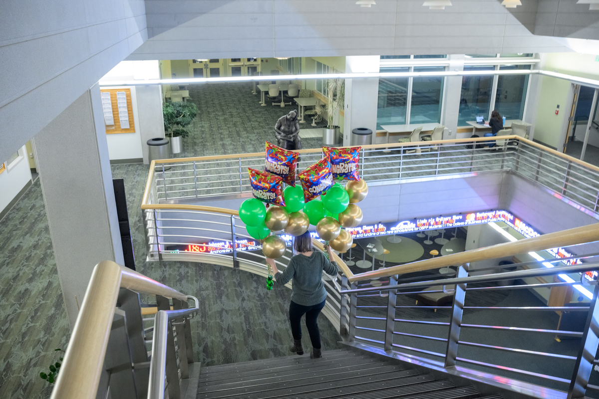 CBPP Enrollment Manager/Graduate Advisor Andrea Jones carries ballons to a classroom in UAA's Rasmuson Hall.