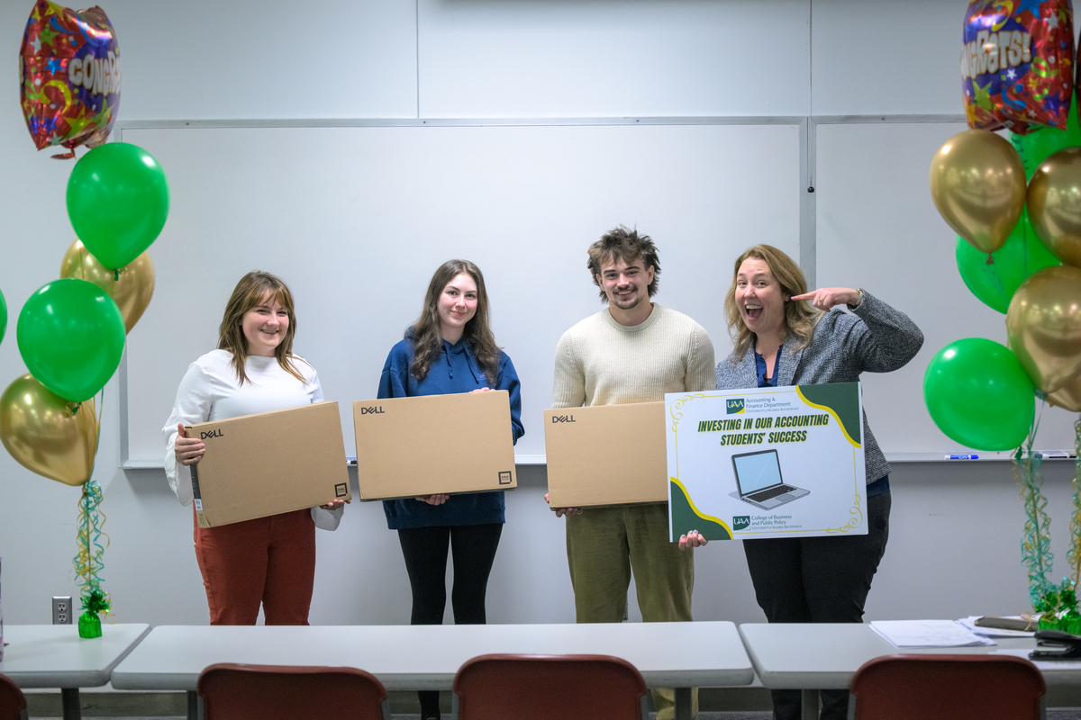 Professor of Accounting Stasia Straley surprises students Cody Jorgensen, Morgan Buwalda, and Brooke Schurosky with new Dell Laptops during class.