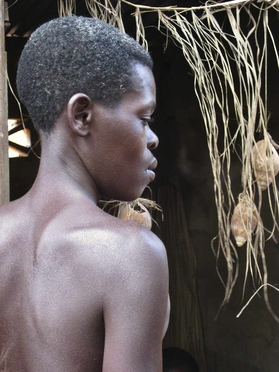 Young man facing strung up grass and shells