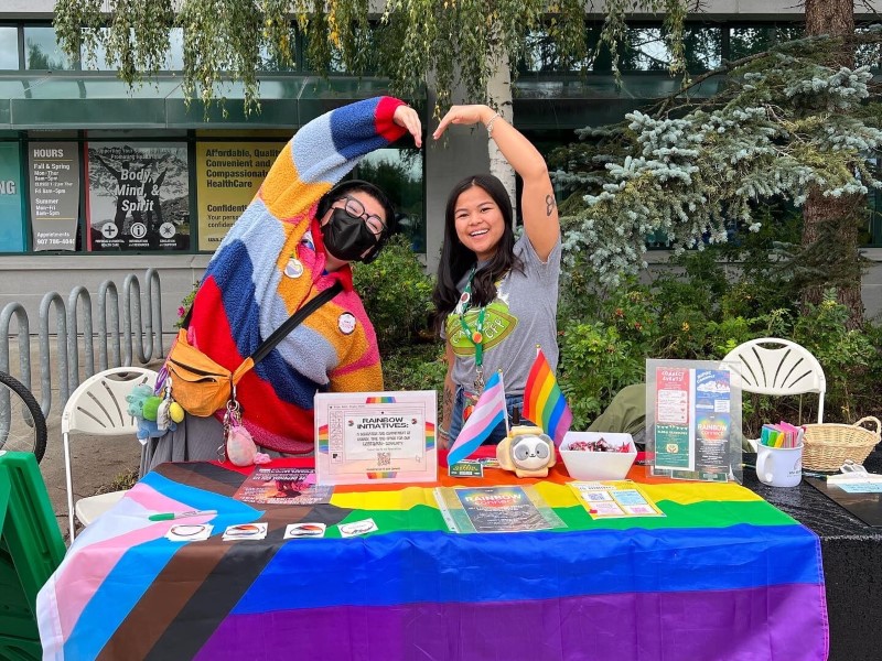 Two friends tabling with pride items.