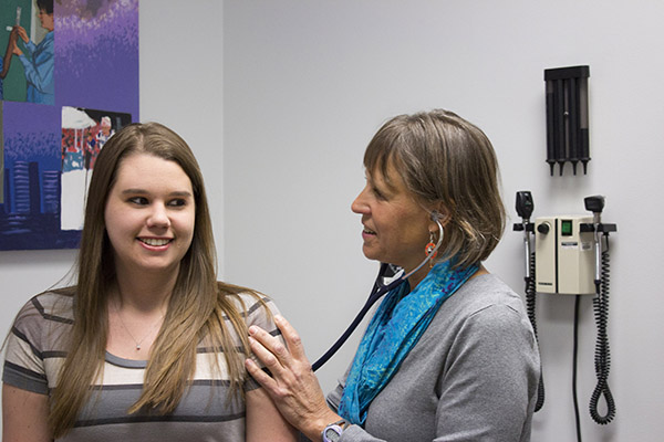 A nurse holds a stethoscope up to a student patient