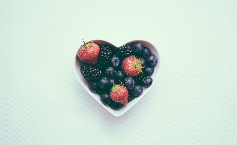 Berries sit in a heart-shaped bowl.