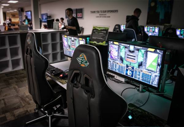 View of gaming computer and chair stations in the UAA Esports Lounge.